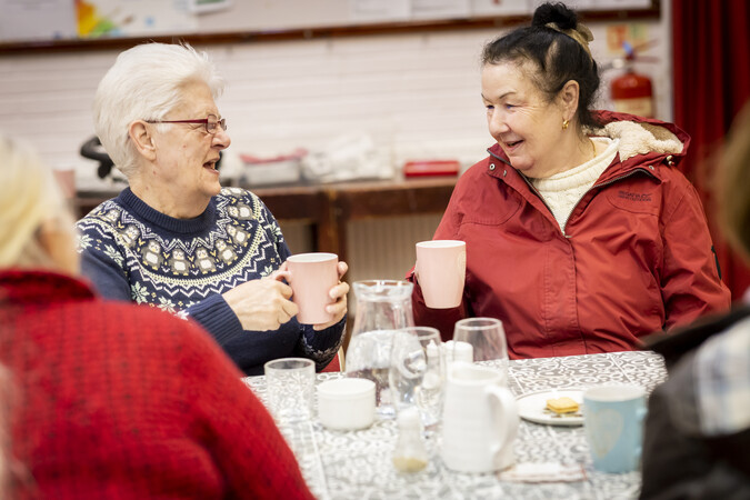 Group gathering, two women talking and drinking tea