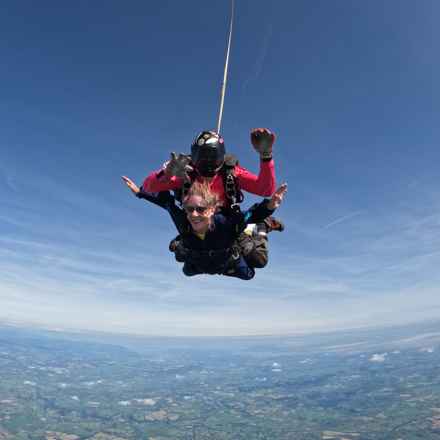 Janet Burton in mid air as she falls from the sky in a tandem skydive. Her instructor is strapped on top.