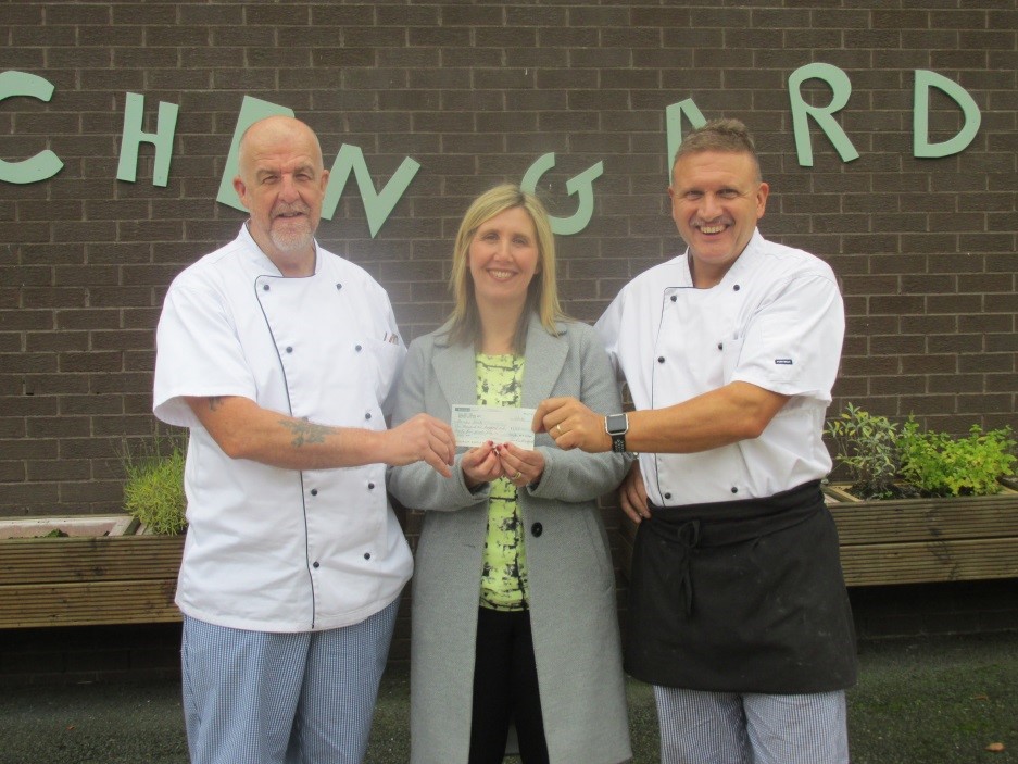 three individuals holding a cheque 