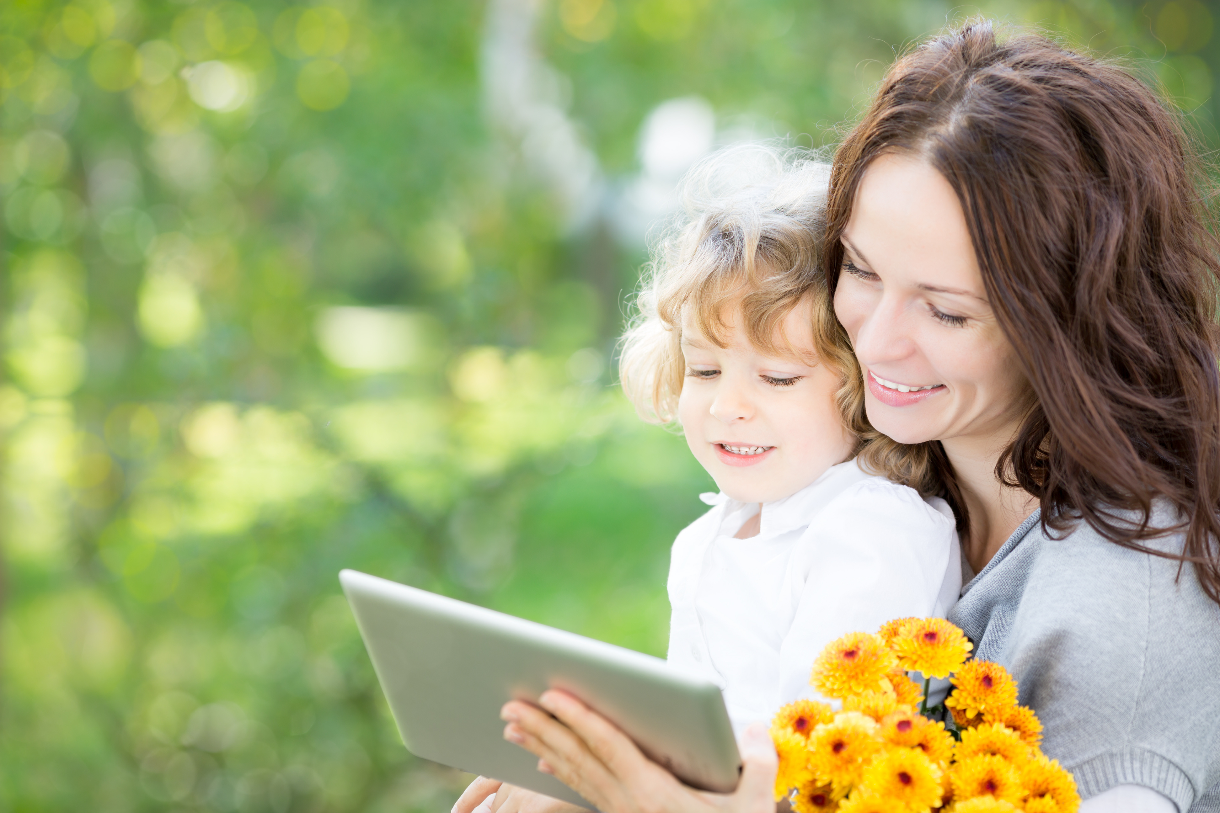 mother and young daughter with flowers looking at tablet