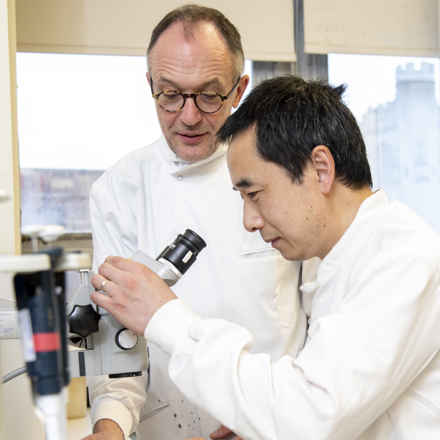 Andrew Dick in lab looking through microscope