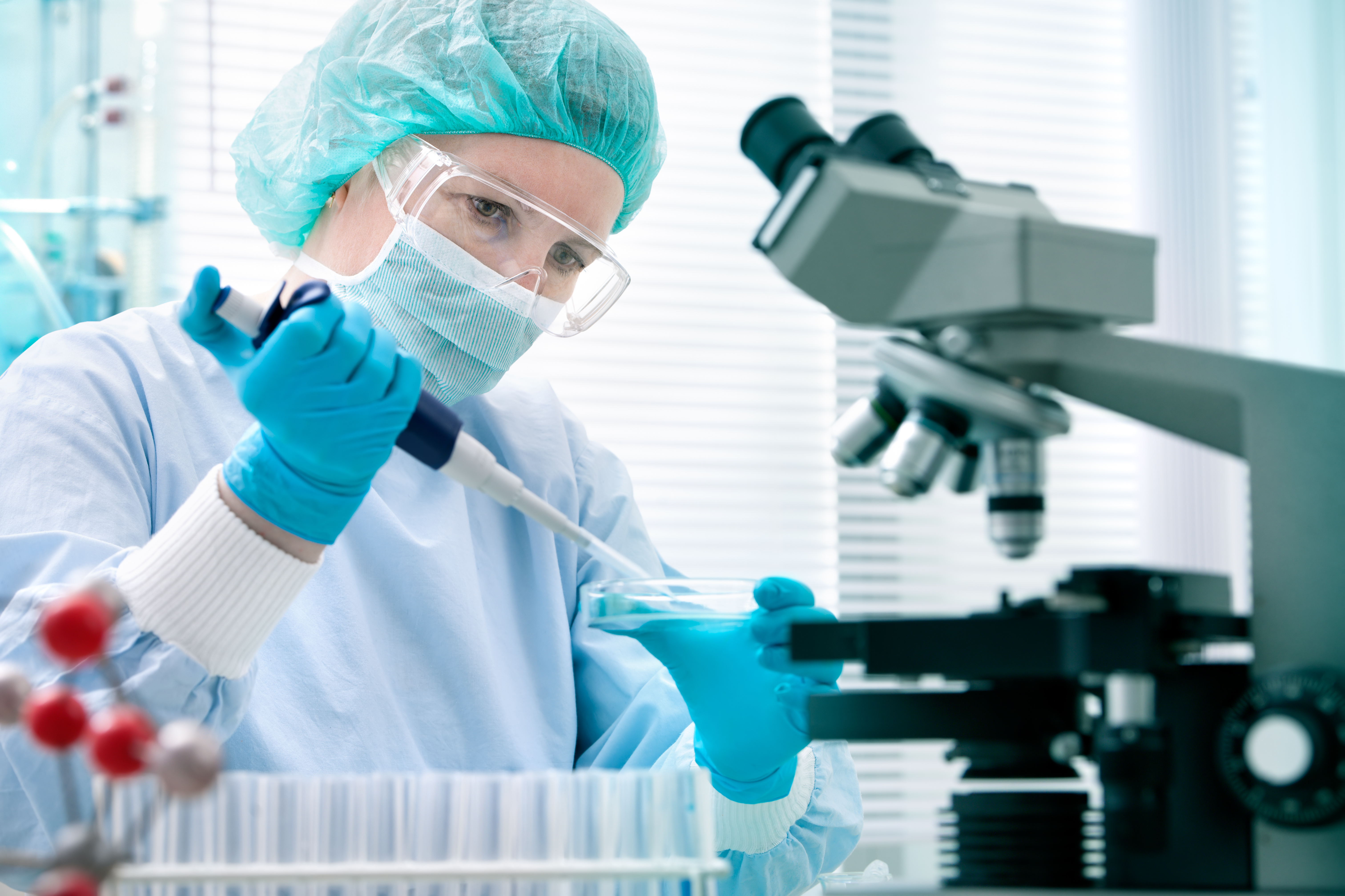 Researcher in laboratory with petri dish and microscope