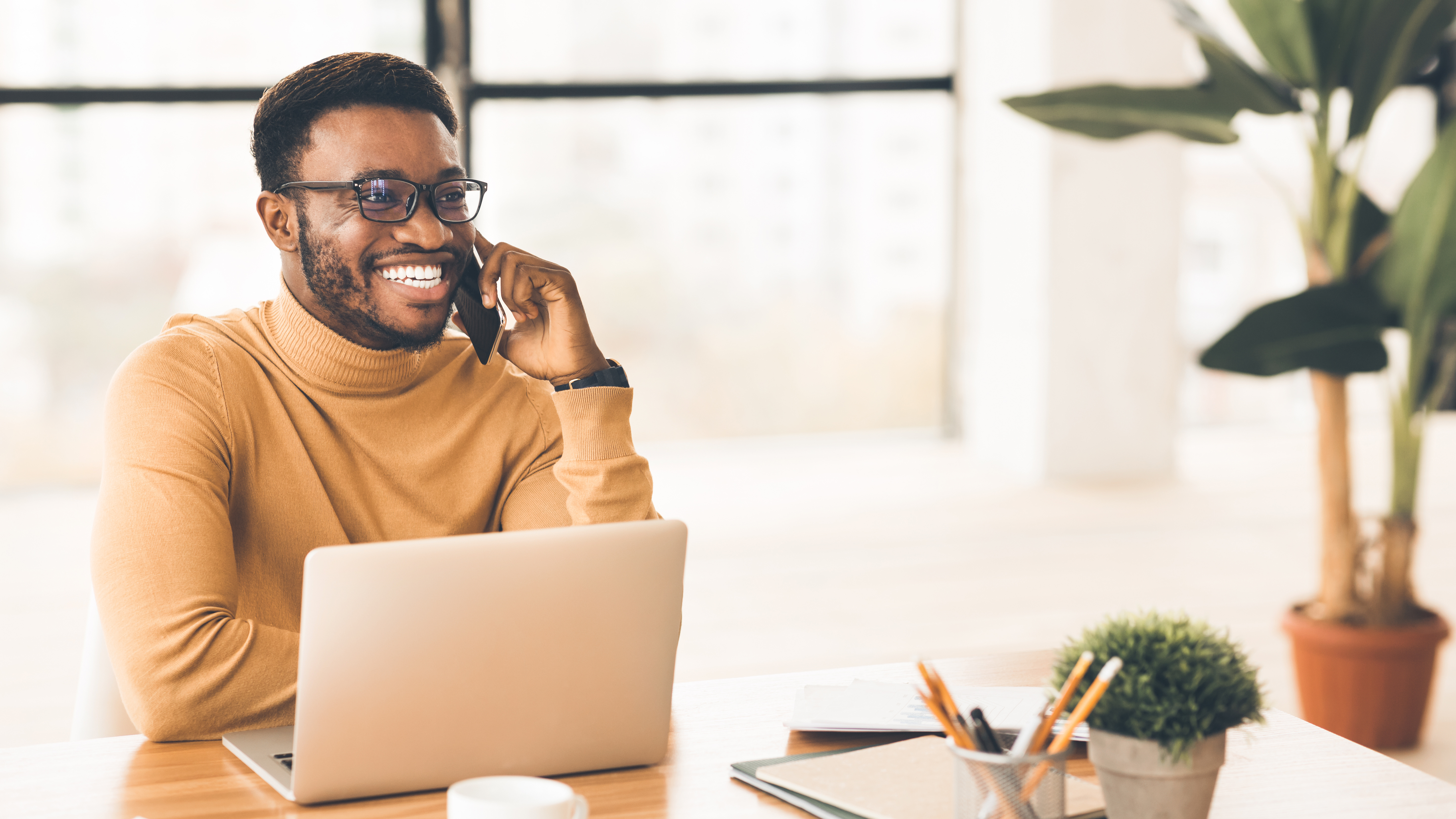 Man smiling on phone at desk