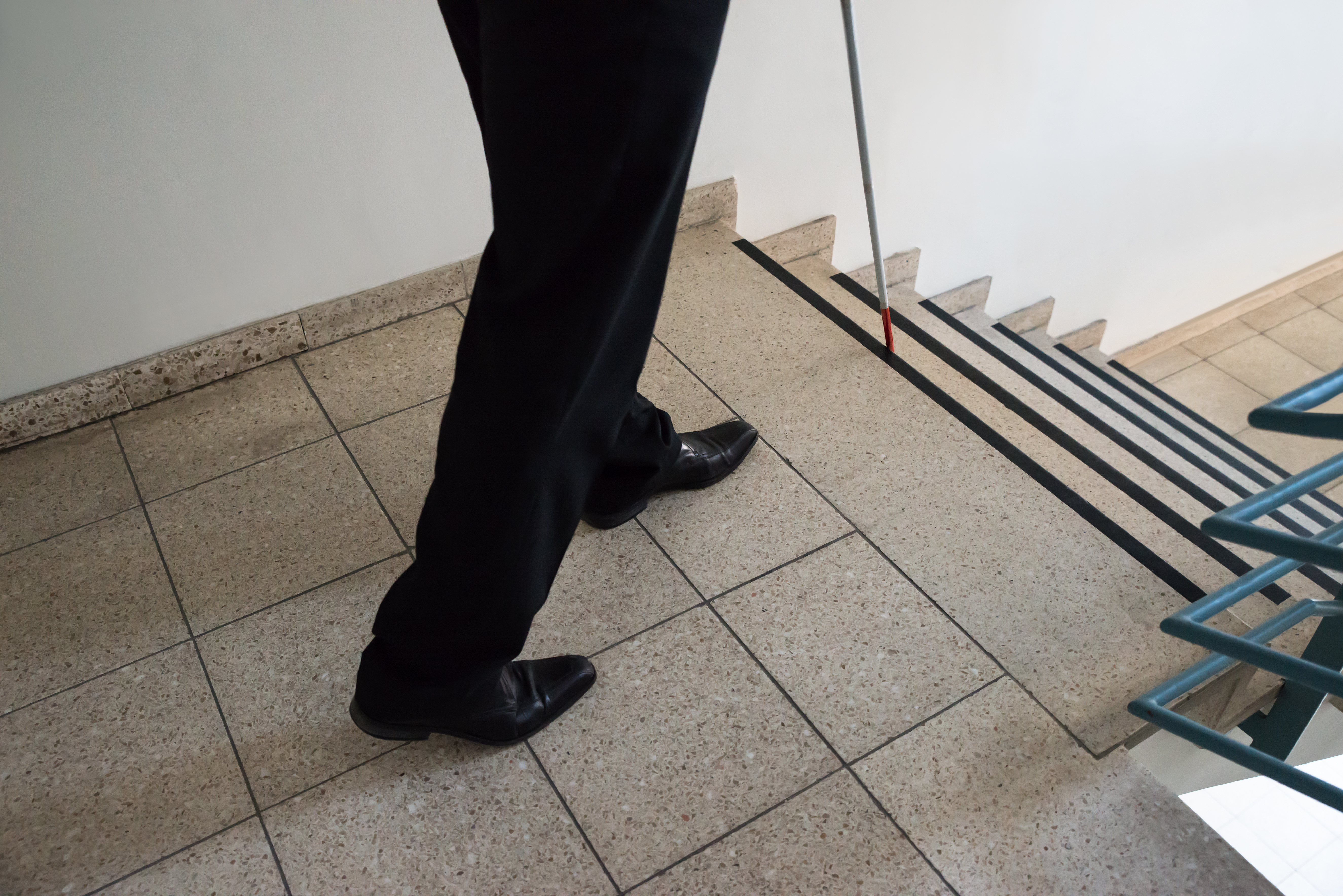 Person walking down the stairs with cane
