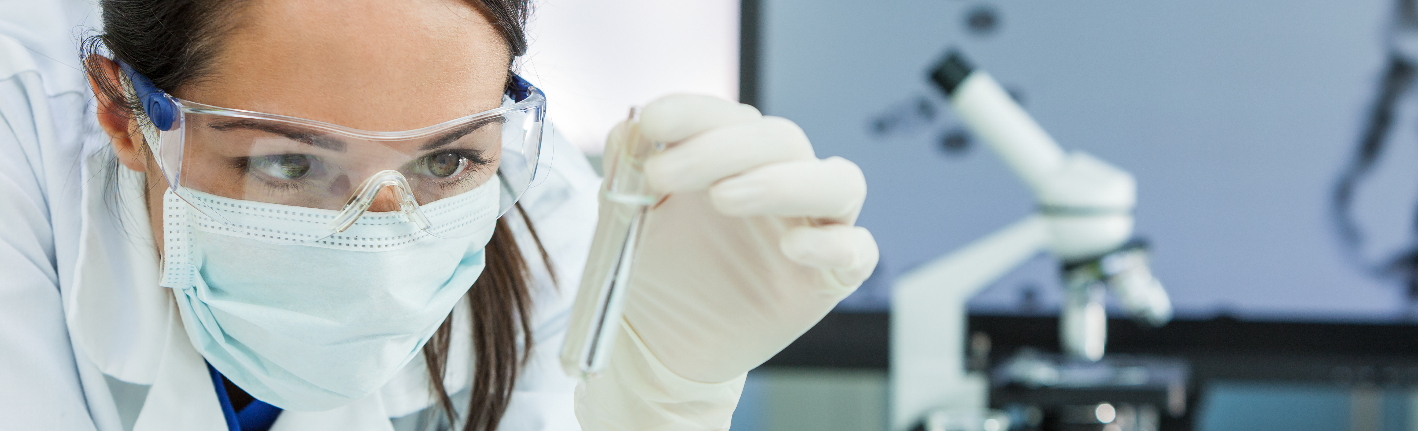 Scientist in a laboratory with a test tube and microscope
